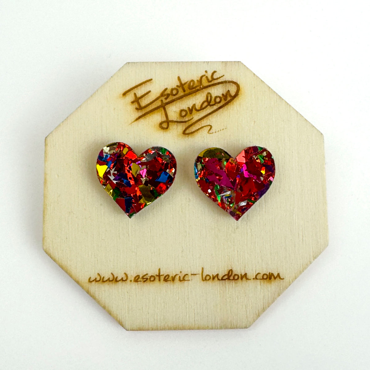 Red confetti glitter heart stud earrings with silver, blue and gold flecks on an octagonal wooden backing card