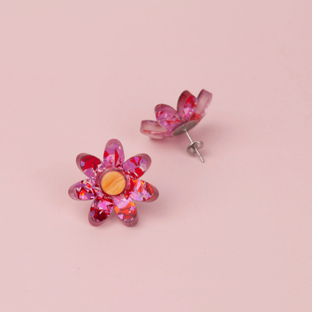 Pink and red confetti flower stud face up with its pair tilted to show the silver post and butterfly back, on pink
