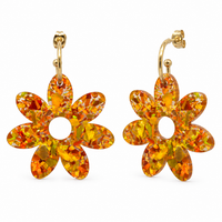 Pair of orange and gold holographic confetti flower earrings with open centres, hanging from gold hoops, on white