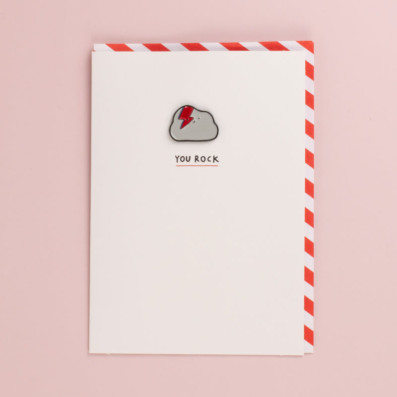 White You Rock card with a grey cloud enamel pin with a red lightning bolt, red and white striped envelope
