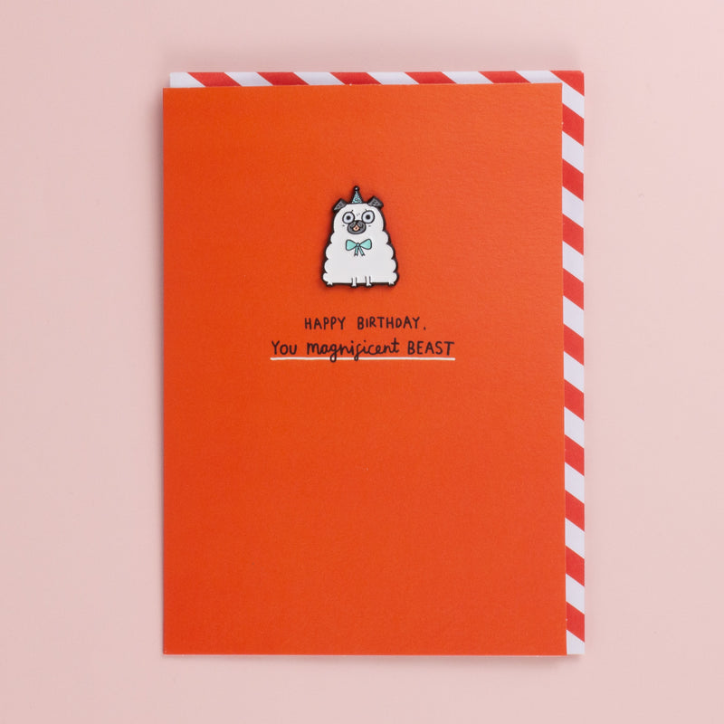 Bright orange birthday card with an enamel pin of a fluffy white pug in a party hat, red and white striped envelope