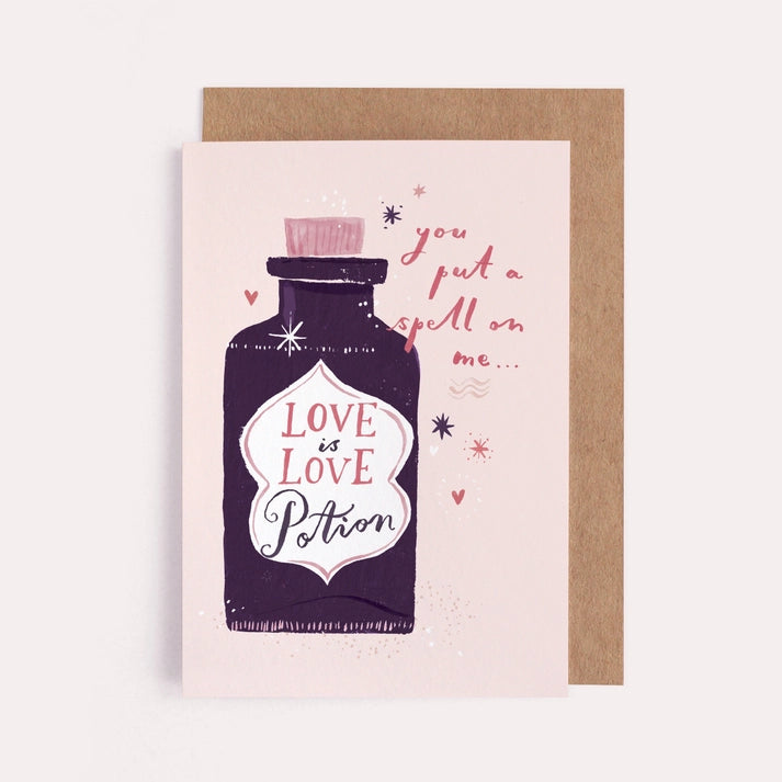 Love potion card with a dark purple potion bottle on pink, reading you put a spell on me, with a kraft envelope